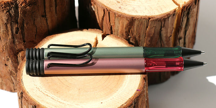lamy_2024_special_edition_al_star_autumn_pink_and_sage_ballpoint_pens_on_wood