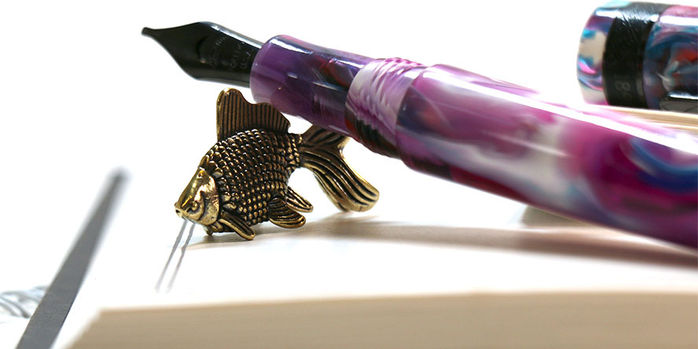 sassy_brassy_goldfish_pen_rests_on_log_of_elixir_archiving_book